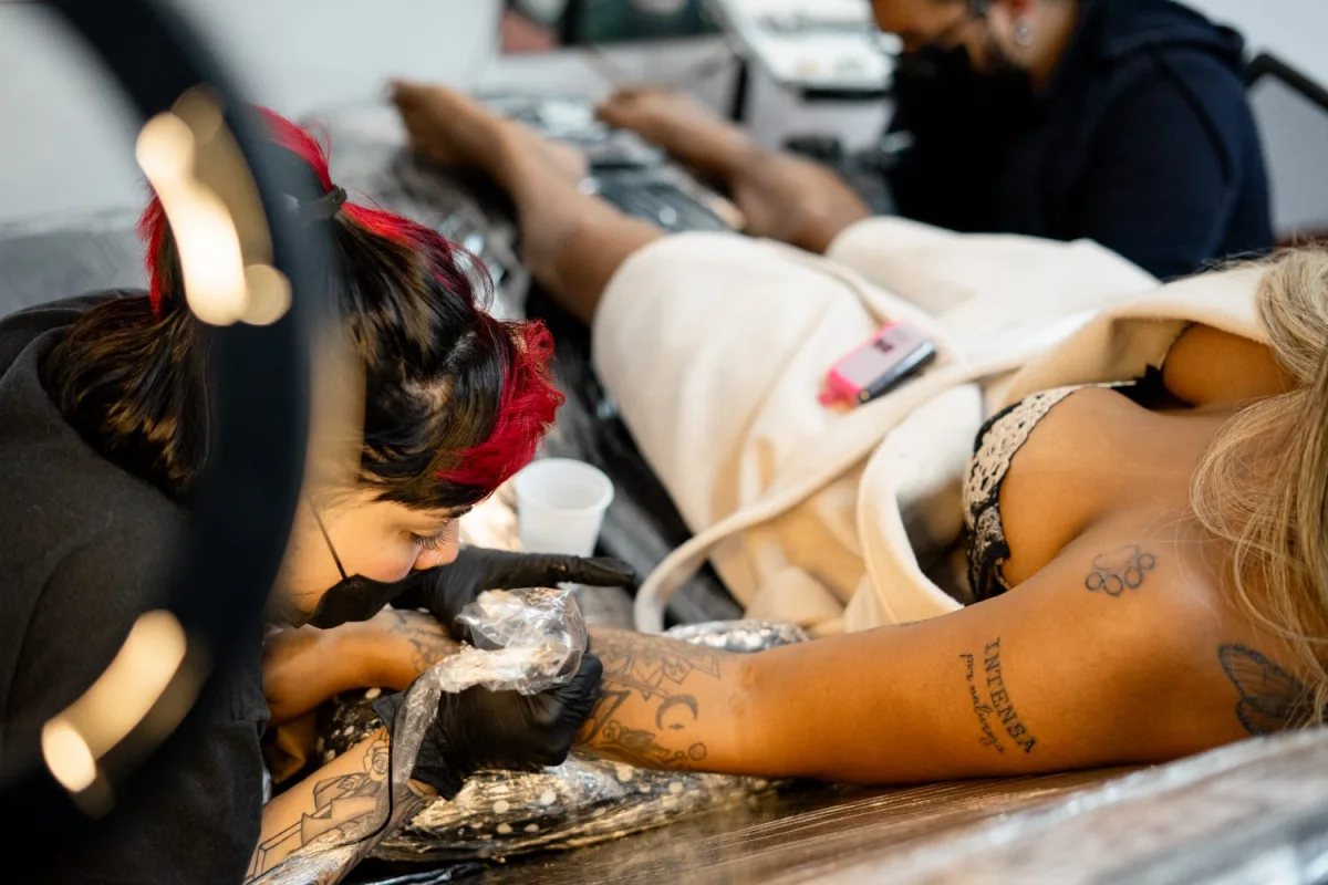 Profissionais da Lágrima Negra realizando tatuagens no estúdio