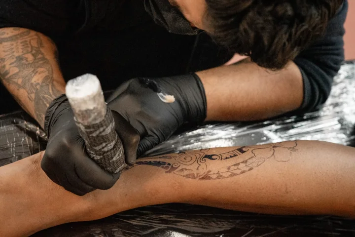 Detalhe de tatuagem sendo realizada com luvas no estúdio